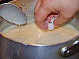 Dropping dough balls into coconut sauce